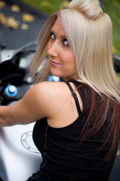 A pretty blonde girl posing on a motorcycle.