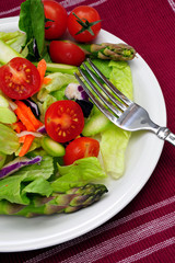 Salad with cherry tomatos, asparagas on a white plate