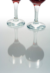 Two goblets with red wine standing on glassy background