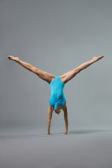 young and beautiful ballet dancer posing on grey