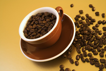 brown cup filled with coffee beans on golden surface