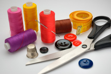 thread coils, measuring tape, thimble, scissors and a needle