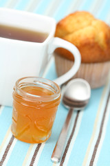 cup of delicious tea with sweet muffin and confiture