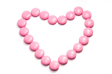 Pills in shape of love heart on white background
