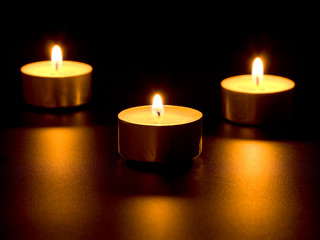 Three burning candles isolated on black background