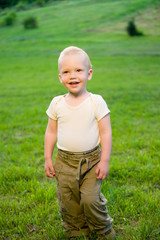 Portrait of smiling little boy on sunny green grass field