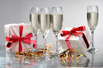 Glasses of champagne, gifts with red tapes and bows