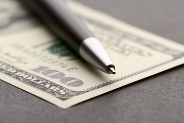 Close-up of a pen with a one hundred dollar bill