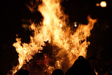 People are standing front of huge fire