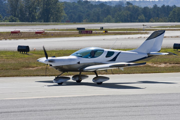 A small single prop plane taxiing across the runway