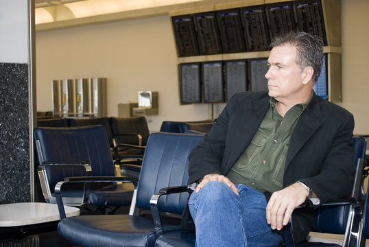 A man seated and waiting in an airport.