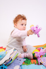 Fototapeta na wymiar One year old red haired baby girl plays with toys. Studio Shot.
