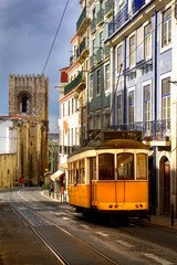 Fototapeta na wymiar Widok starej lizbońskiej ulicy z tradycyjnym tramwajem żółtym