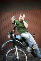 Fototapeta na wymiar Portrait of young man sitting on motorbike and looking at mirror