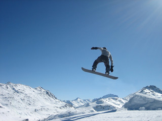 Naklejka na ściany i meble Lot na snowboard na tle śnieżnych gór