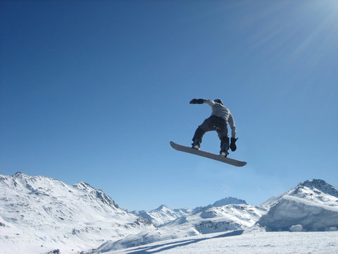 Flight on a snowboard on a background of snow mountains