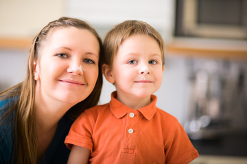 Happy young mother and son baking. Flour on theirs faces.