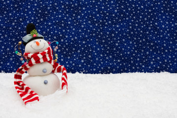 Snowman sitting on snow with a star background