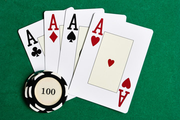 Casino chips and four aces on green felt