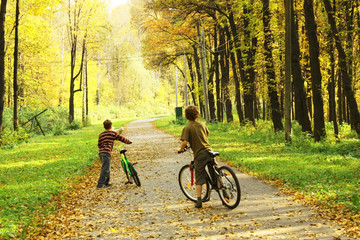 Two boys dismount bicycles and watching forward