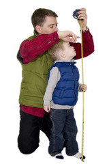 Father measuring son with a measuring tape