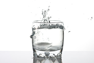shot of water splashing from ice  being dropped in a glass.