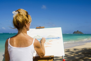 Obraz premium A female artist painting on the beach in Hawaii