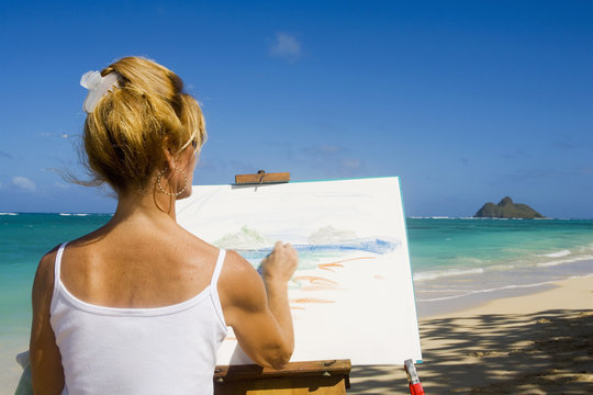 A female artist painting on the beach in Hawaii