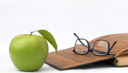 Apple, glasses and open book isolated on white background