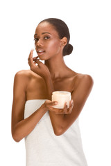 Afro-American girl wrapped in towel putting cream on face