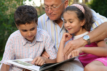 Grandfather and kids reading book