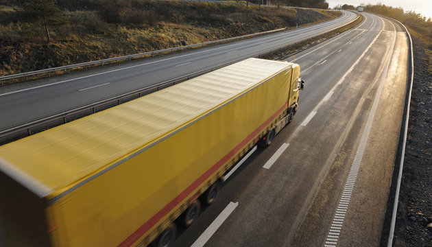 yellow truck speeding into sunset