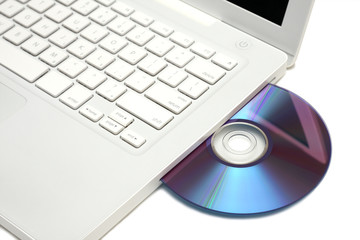 White laptop with dvd disk in slot isolated.