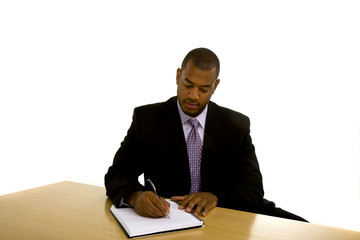 Black Man Writing at Desk Looking Down