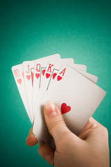 Hand and playing cards on green background