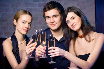 Two young women and man with champagne glasses