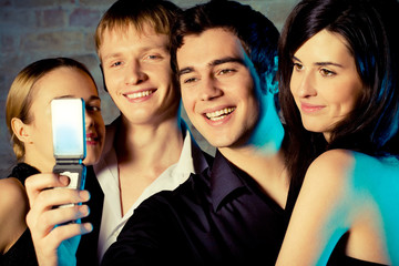 Young embracing smiling people taking photograph and posing at c