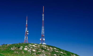 Telecommunication tower on the green field with blue sky