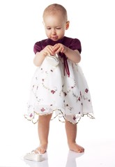 Cute baby in a dress standing on white background