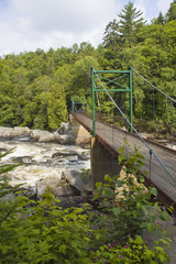 a metal bridge crossing a rapid river