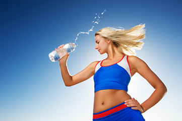 Young woman drinking water after fitness exercise