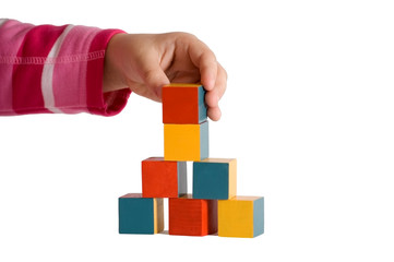 Child hand building a tower of colored blocks