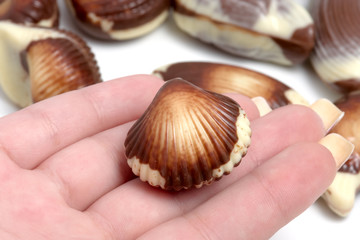 Girl holding chocolate  sea shell against white