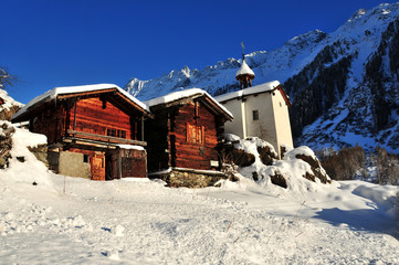 two old chalets and a chapel in the snow