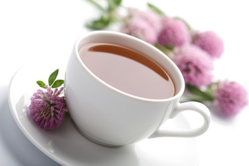 white cup of herbal tea and clover flowers isolated