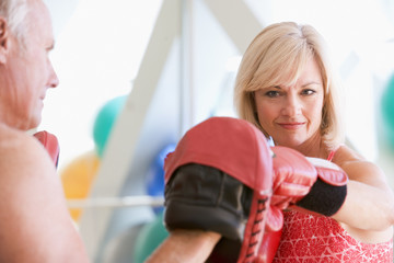 Woman Boxing With Personal Trainer At Gym