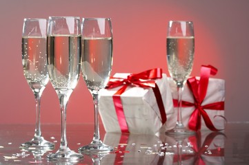 Glasses of champagne, gifts with red tapes and bows