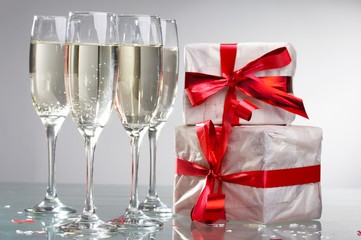 Glasses of champagne, gifts with red tapes and bows