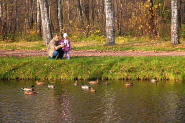 Grandfather with granddaughter in wood look on ducks