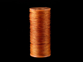 Close-up of the orange strong thread spool isolated on black